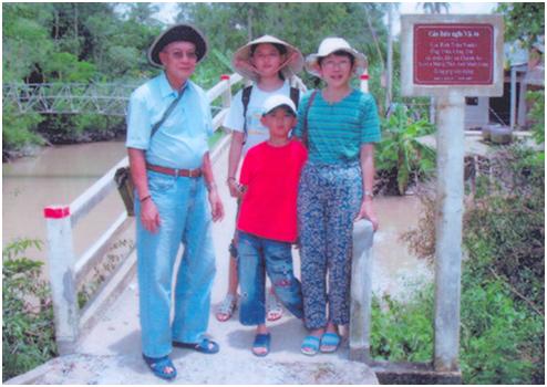 Vợ chồng ông Thomas Soi và hai con chụp ảnh bên chiếc cầu gia đình ông trao tặng làng quê Việt Nam. Ảnh: V.K.